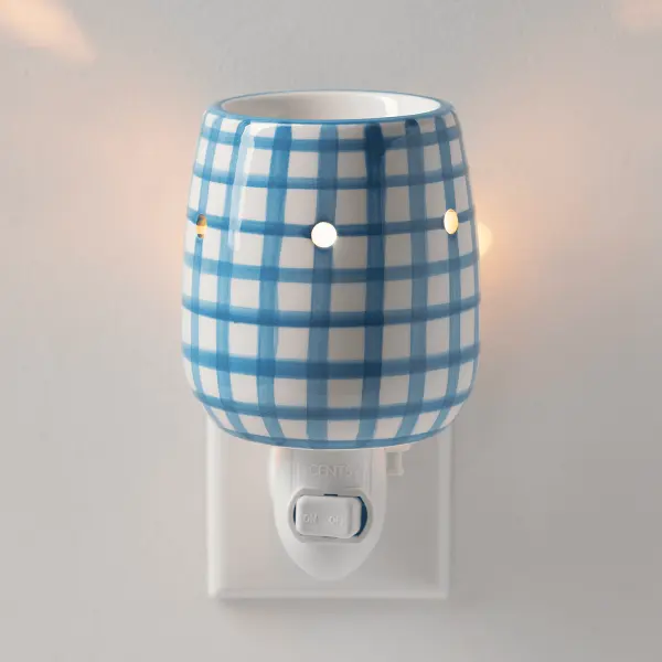 The Scentsy Cottage Gingham Mini Electric Fragrance Melter featuring a white ceramic base with a hand-painted blue checked pattern and glowing vent holes.