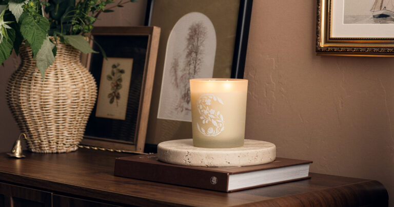 A glowing safe scented candle sitting on a rustic wooden table enhancing home ambiance.
