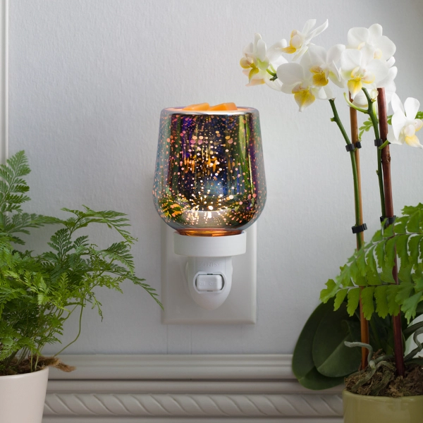 Scentsy Stargaze Mini Wax Warmer plugged into a wall, glowing with a vibrant, iridescent 3D starburst glass effect.