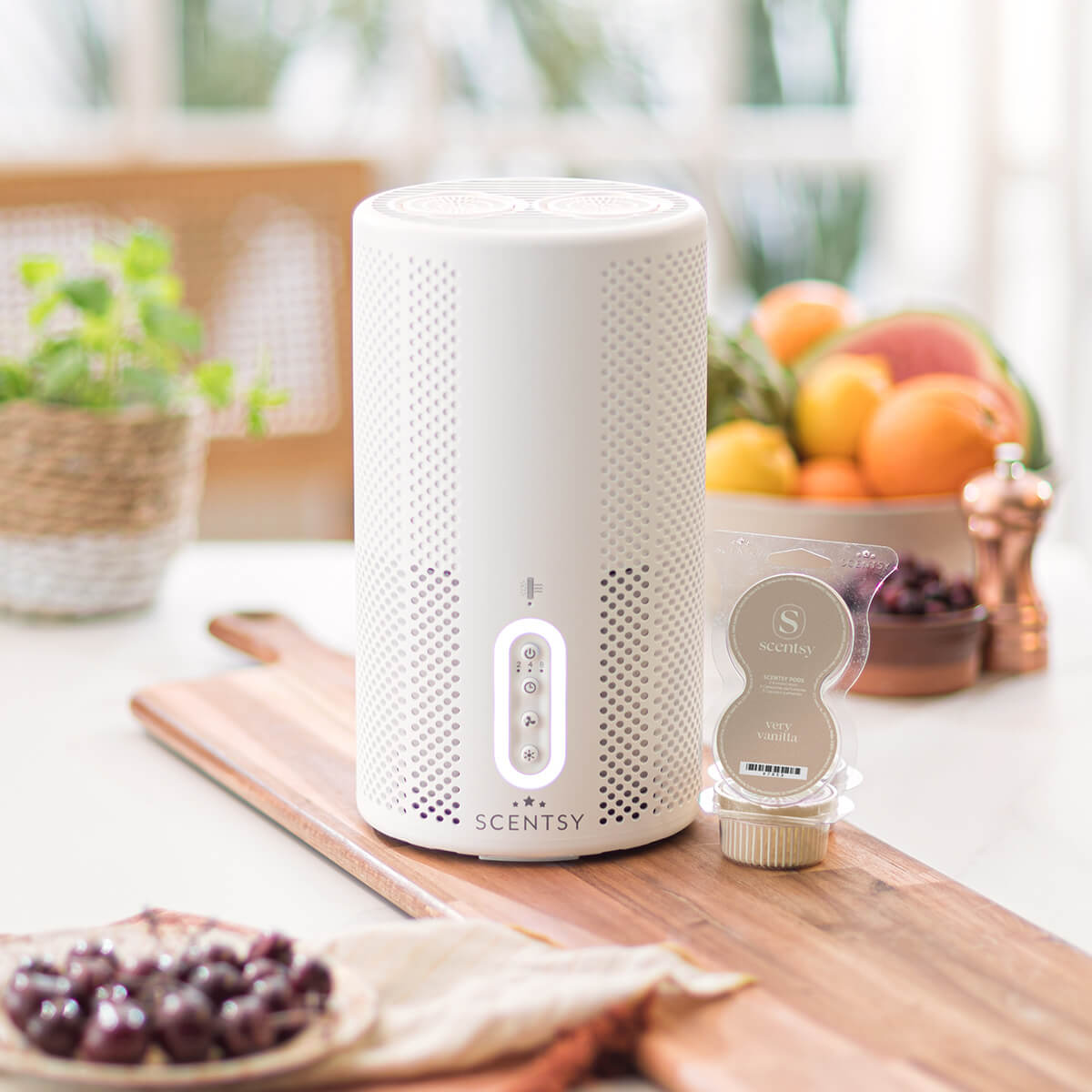 A Scentsy Air Purifier in black is next to an open Scentsy Pod Twin Pack on a kitchen counter.