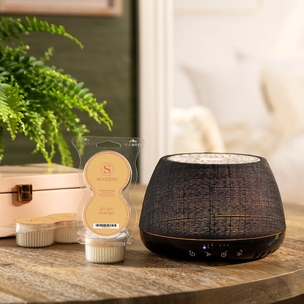 A Scentsy Air Quad Black – Crosshatch is on a table next to an open Scentsy Pod Twin Pack.