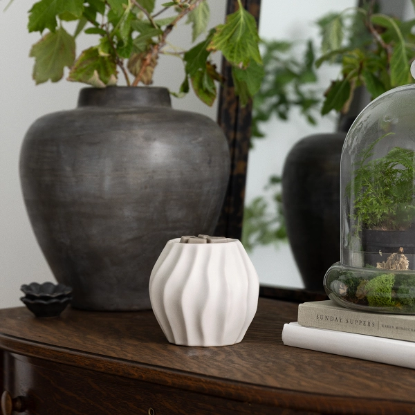 A 5-inch white ceramic Scentsy Cascade Electric Fragrance Melter featuring swirling fluid ridges on a dark wooden vanity.