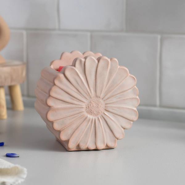 The Scentsy Daisy Wax Warmer in a pale blush pink ceramic featuring a large, hand-carved floral design and ribbed sides.
