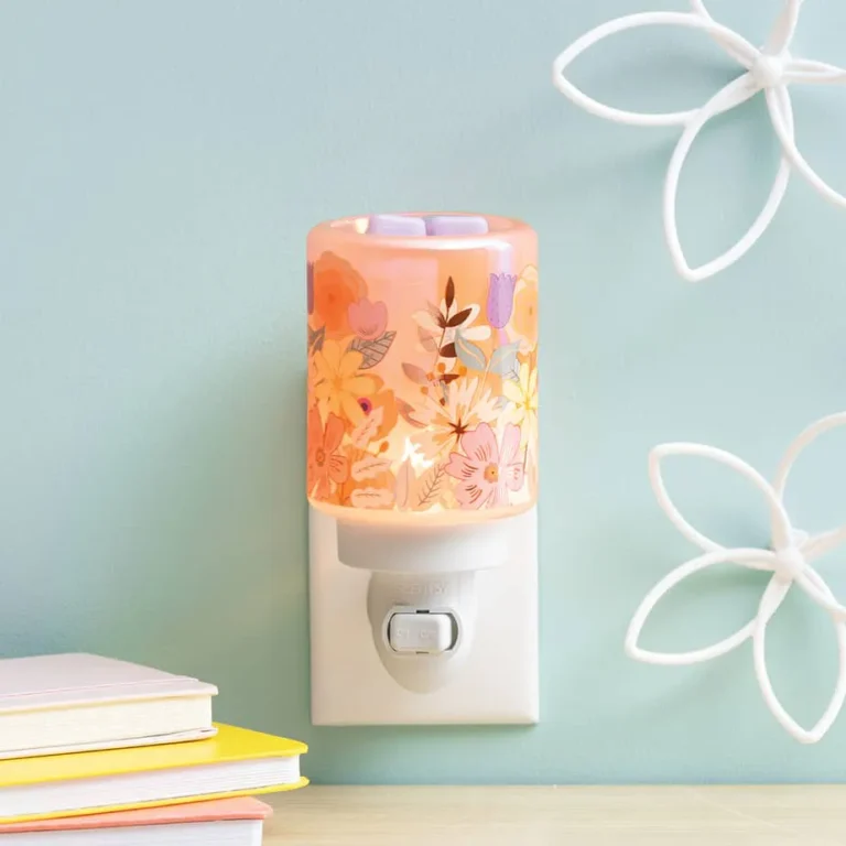 Scentsy Daydream Mini Wax Warmer plugged into a wall, featuring soft pink frosted glass adorned with glowing, delicate floral silhouettes.