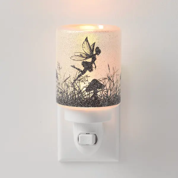 The Scentsy Fairy Glade Mini Wax Warmer glowing warmly with a textured glass bead finish and a black silhouette of a fairy and mushrooms.