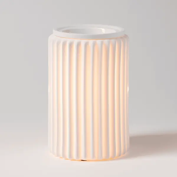 The Scentsy Fluted Glow Electric Fragrance Melter featuring matte white porcelain with vertical fluting radiating a warm, glowing light.