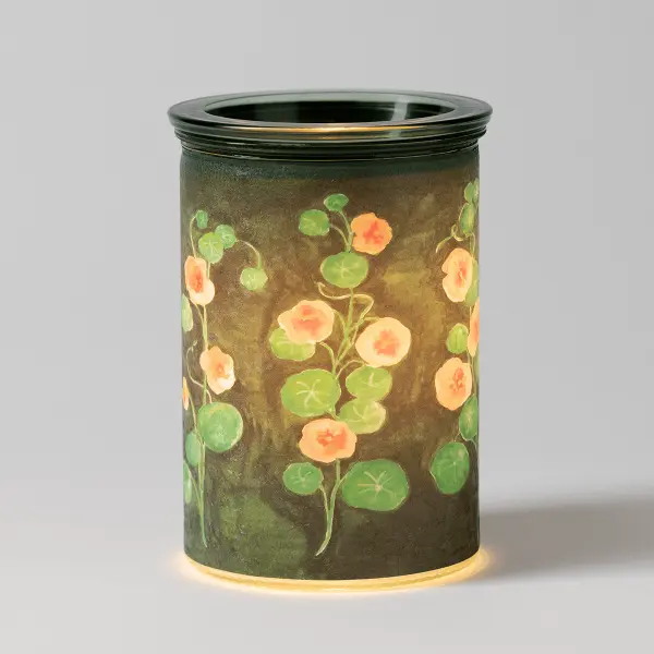 The Scentsy Garden Whimsy Electric Fragrance Melter glowing warmly with a watercolor painted design of orange flowers and green leaves.