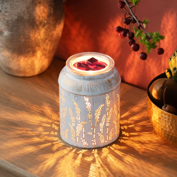 The Scentsy Golden Grain Wax Warmer in a distressed whitewashed metal finish glowing warmly through stamped wheat and grain cutouts.