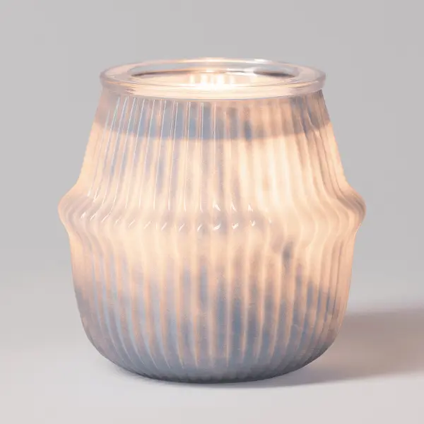 The Scentsy Gossamer Haze Wax Warmer glowing warmly, featuring soft pale blue frosted glass with playful art deco fluted curves.