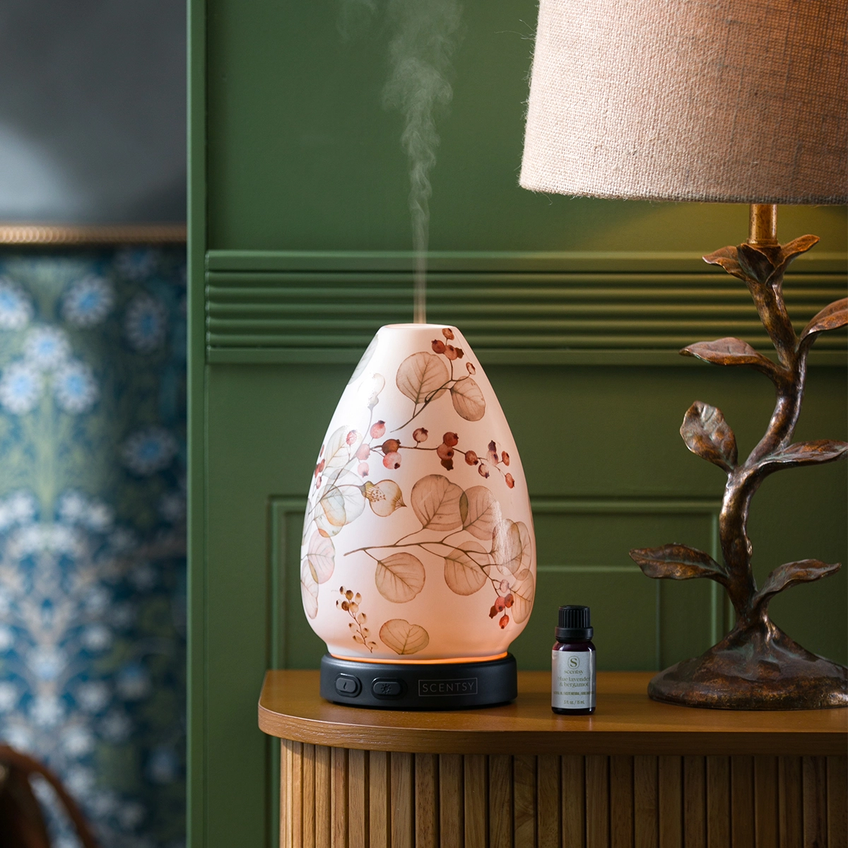 The Scentsy Grow Diffuser glowing with delicate watercolor botanical vines on a wooden table, releasing a cool mist.