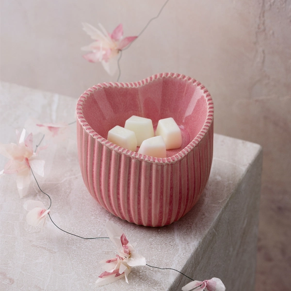 The Scentsy Heart of Hope Wax Warmer in pink ceramic with a textured, ribbed finish and wax cubes inside.