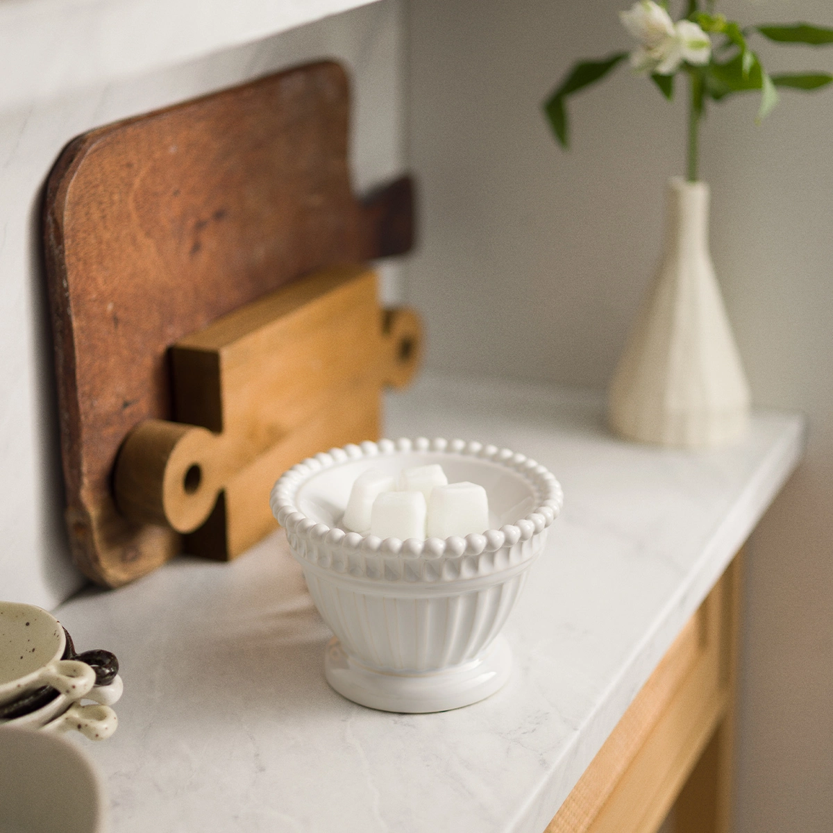 Scentsy Heirloom Wax Warmer sitting on a table, featuring a classic fluted bowl design finished in a glossy ivory reactive glaze.