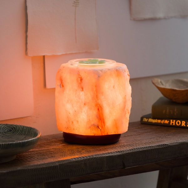 The Scentsy Himalayan Salt Wax Warmer glowing warmly, featuring a genuine, hand-carved pink rock salt body on a dark wooden base.