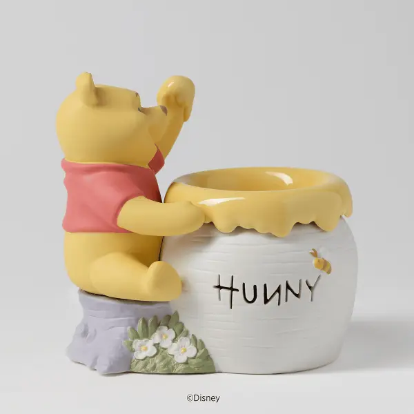 The Scentsy Just A Smackerel of Hunny Wax Warmer features Winnie the Pooh reaching into a white pot overflowing with golden dripping honey.