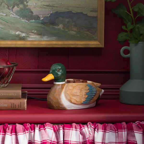 Scentsy Mallard Wax Warmer sitting on a red shelf beside books, featuring a hand-painted ceramic duck design.