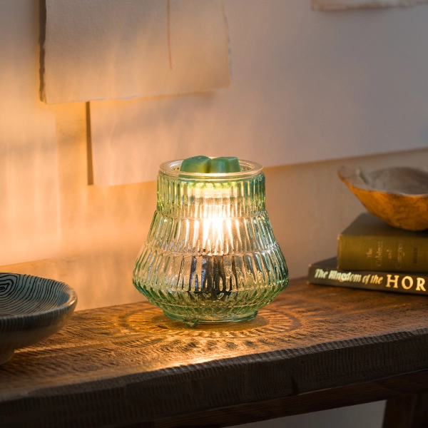 Scentsy Moroccan Mint Wax Warmer glowing on a wooden table, featuring ribbed green glass that casts intricate light patterns.