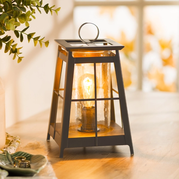 Scentsy Shining Light Wax Warmer featuring a matte black metal lantern frame with a glowing 40W bulb and clear glass sleeve.