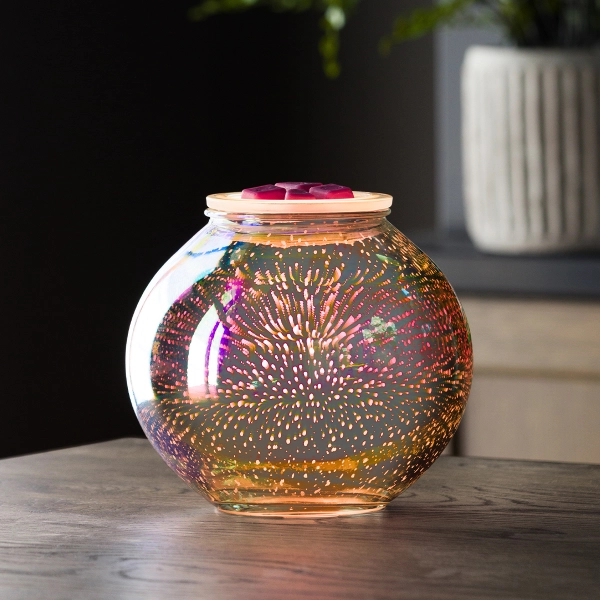 Scentsy Stargaze Wax Warmer glowing on a wooden table, featuring a spherical glass body radiating a vibrant 3D cosmic starburst effect.