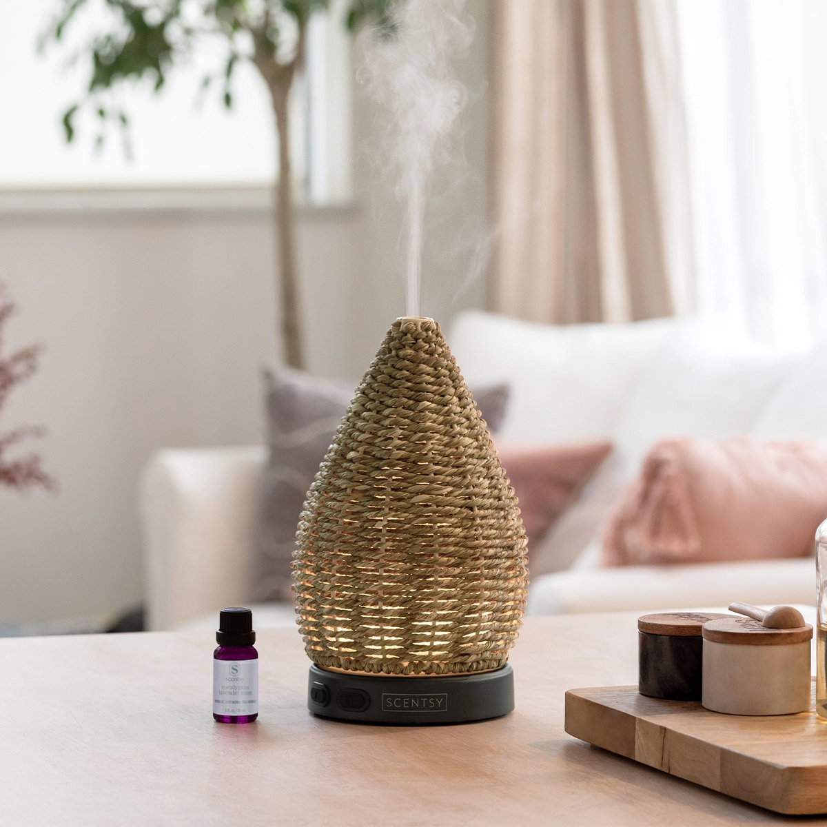 The Scentsy Wonder Diffuser featuring a beautifully hand-woven natural jute rope shade resting on a wooden table next to a bottle of essential oil.